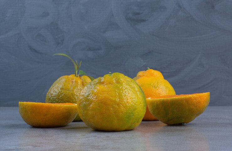 sliced-whole-tangerines-arranged-marble-background_114579-51221